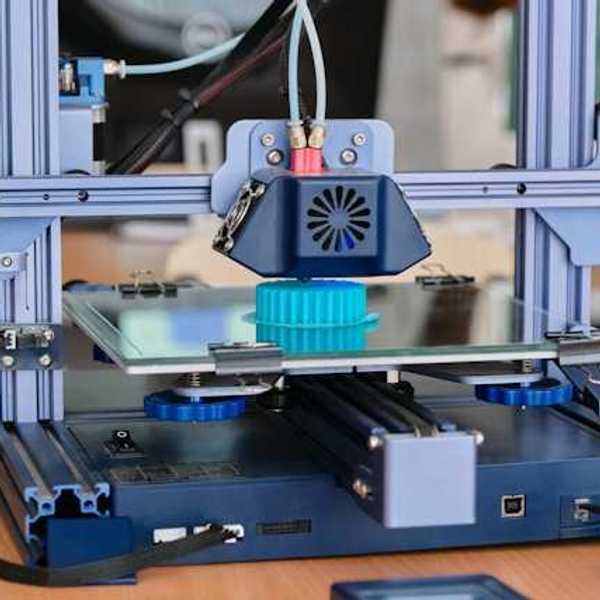 A 3D printer with a small plastic blue item being printed