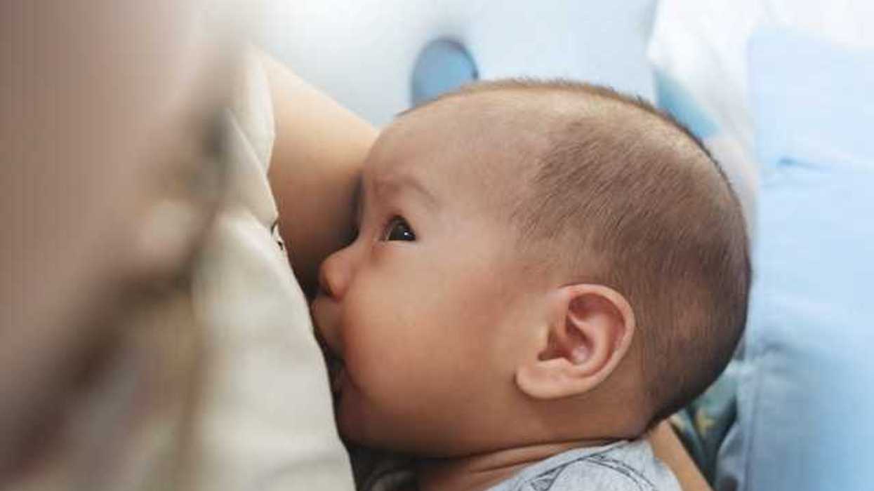 A baby breastfeeding while looking up at his mother