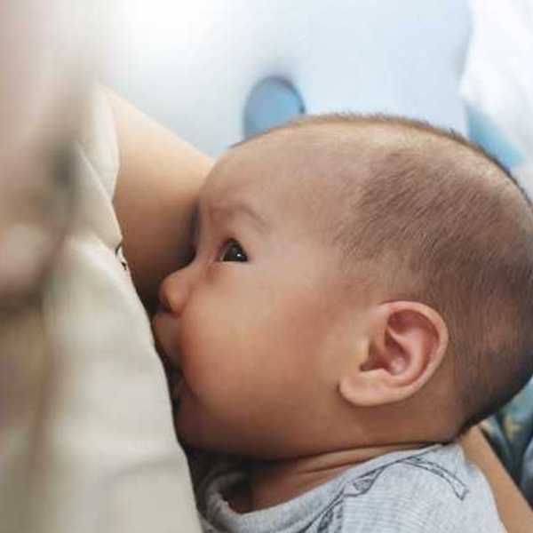 A baby breastfeeding while looking up at his mother