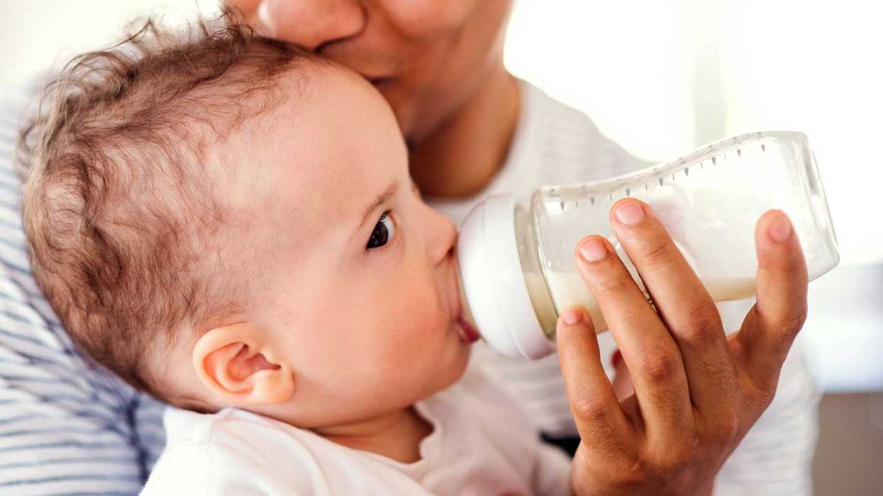 A baby drinks from a plastic baby bottle