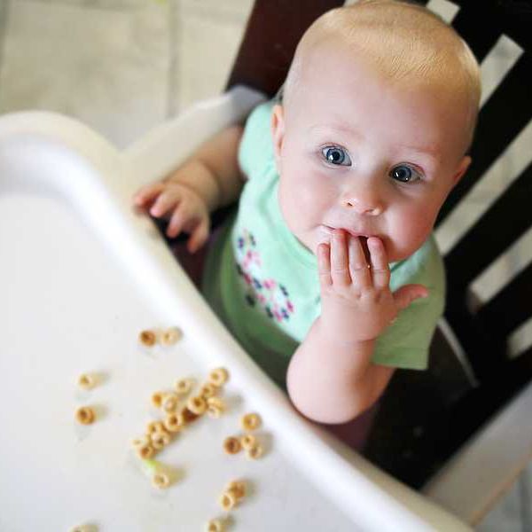 A baby eating cereal in a high chair