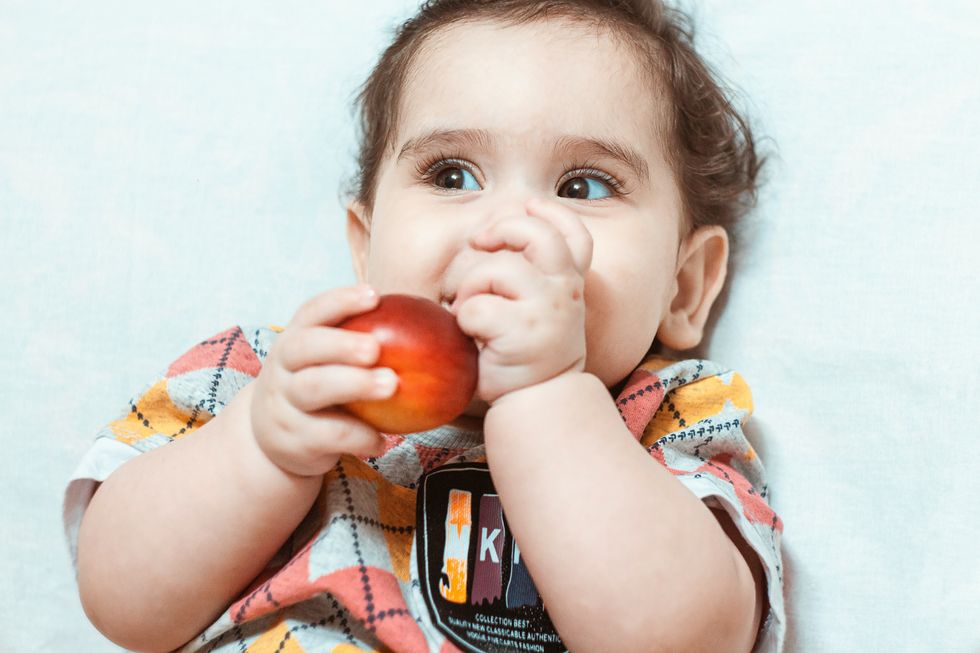 A baby holding a nectarine.