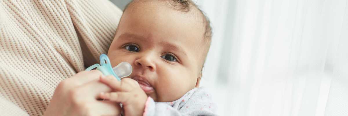 A baby hols a blue pacifier