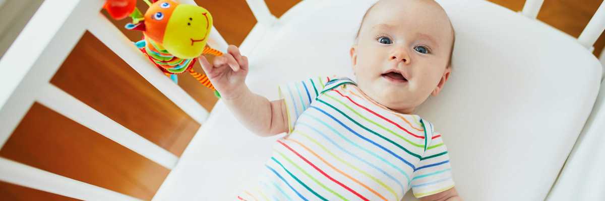 A baby plays in a crib