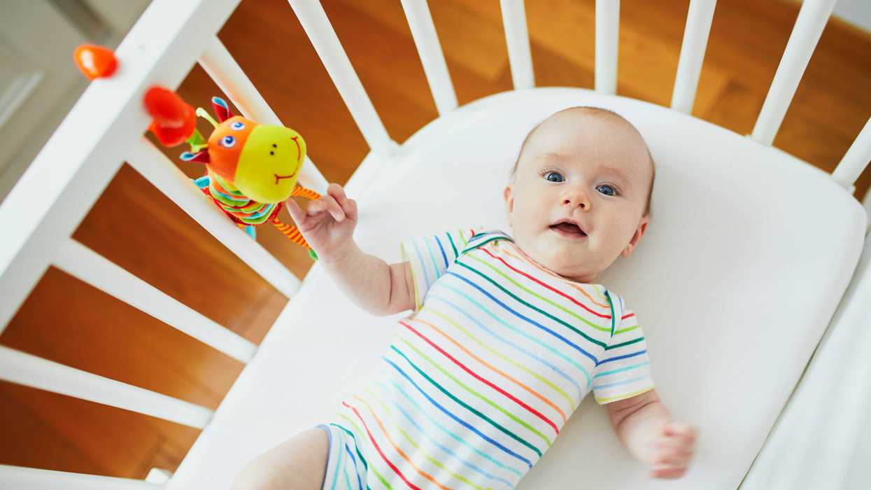 A baby plays in a crib