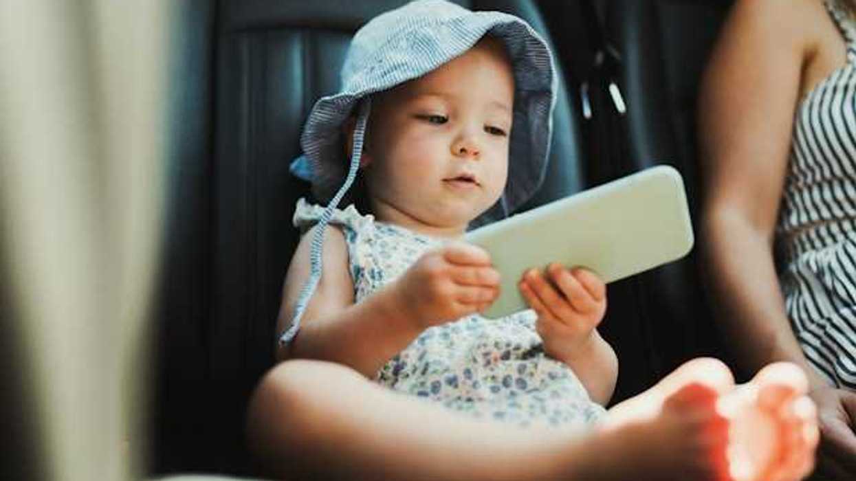 A baby sitting in a car holding a cell phone