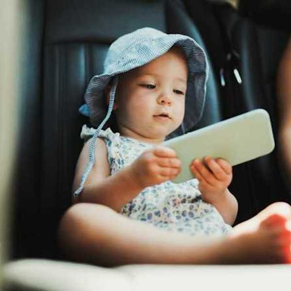 A baby sitting in a car holding a cell phone