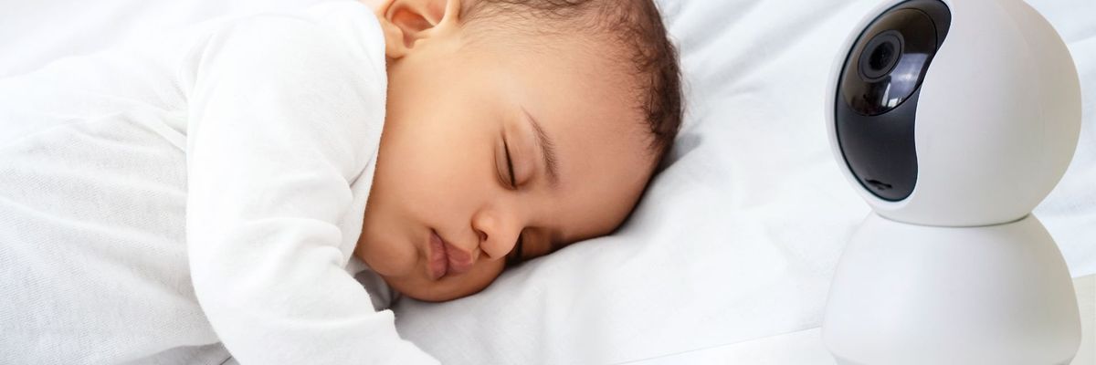 A baby sleeps next to a baby monitor