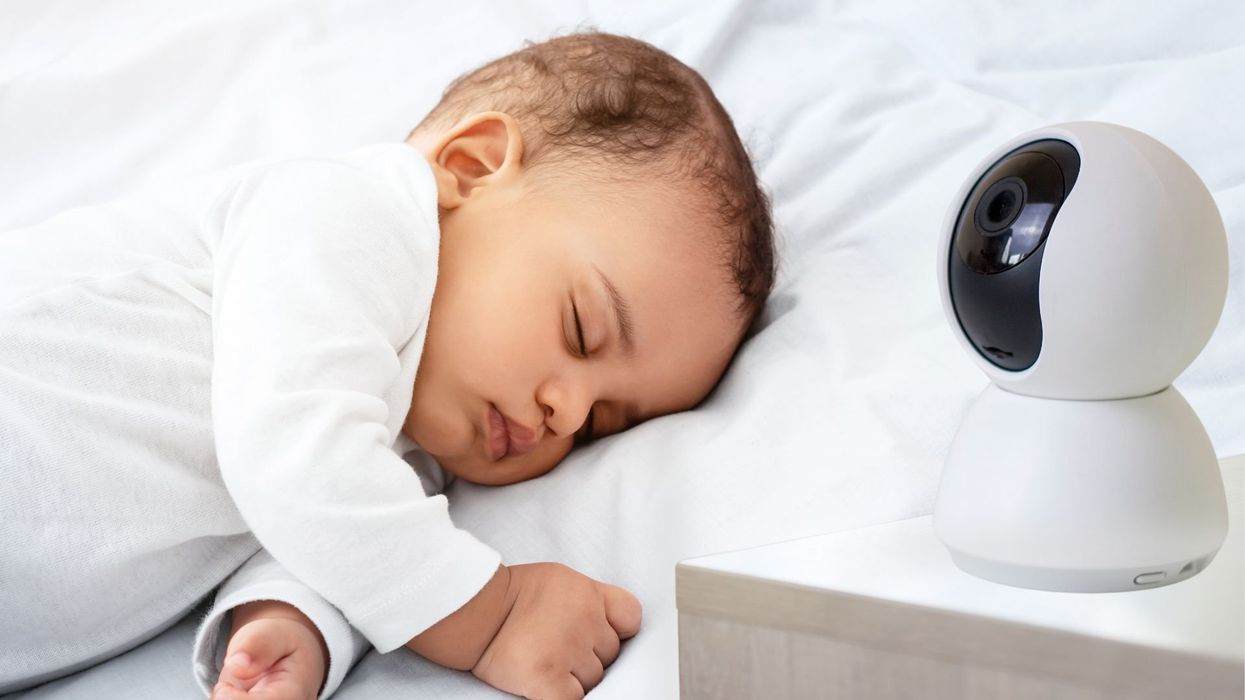A baby sleeps next to a baby monitor