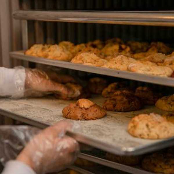 A baker placing baked goods on a tray