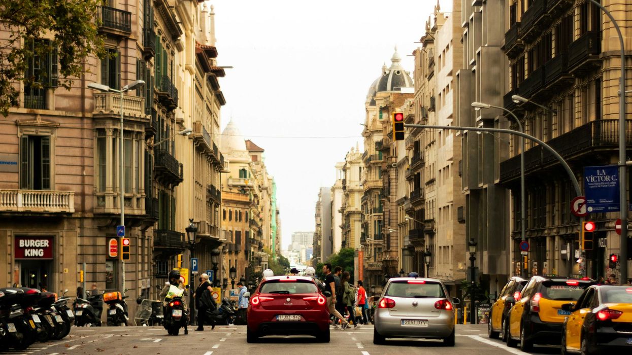 a Barcelona street filled with lots of traffic next to tall buildings.