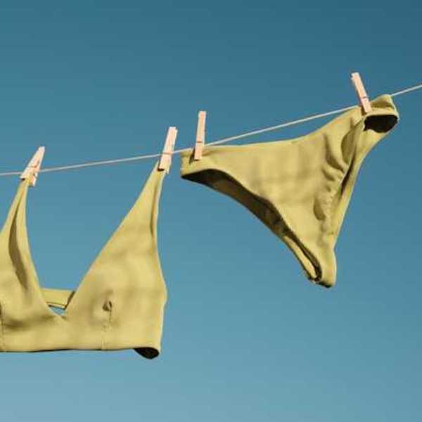 A bathing suit hanging on a line drying in the sun