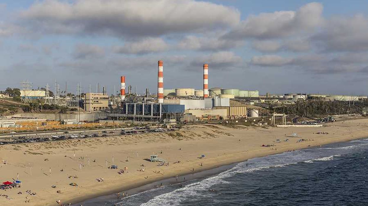 A beach with an oil refinery in the background