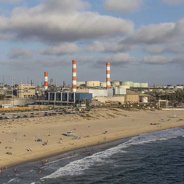 A beach with an oil refinery in the background