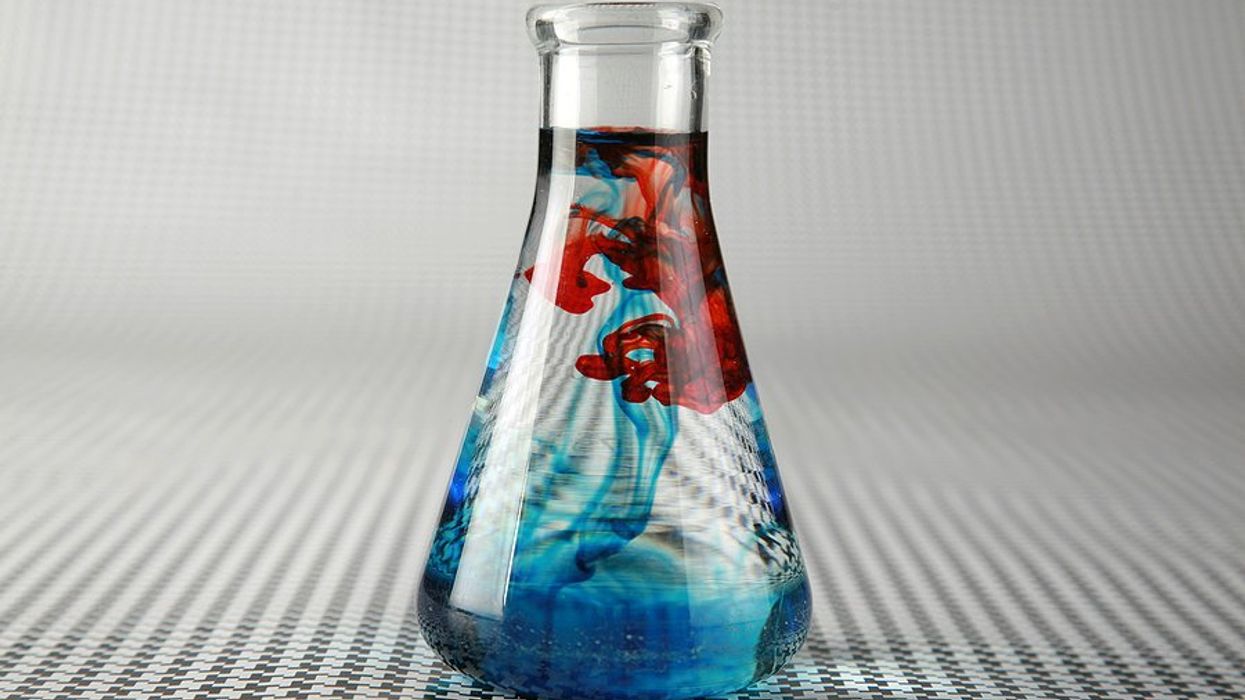A beaker full of blue and red colored water.