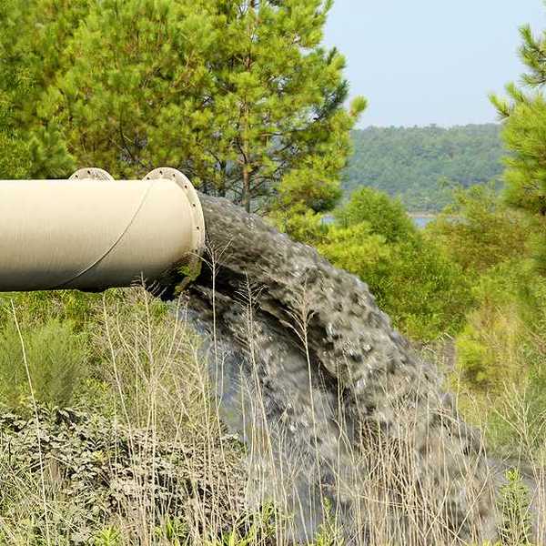 A beige pipe emitting polluted water into a stream