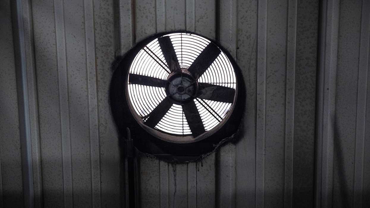 A black and white photo of a circular fan in a wall