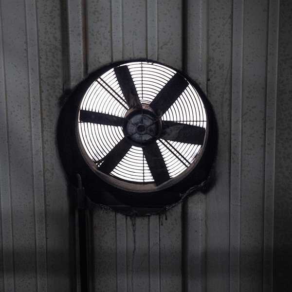 A black and white photo of a circular fan in a wall