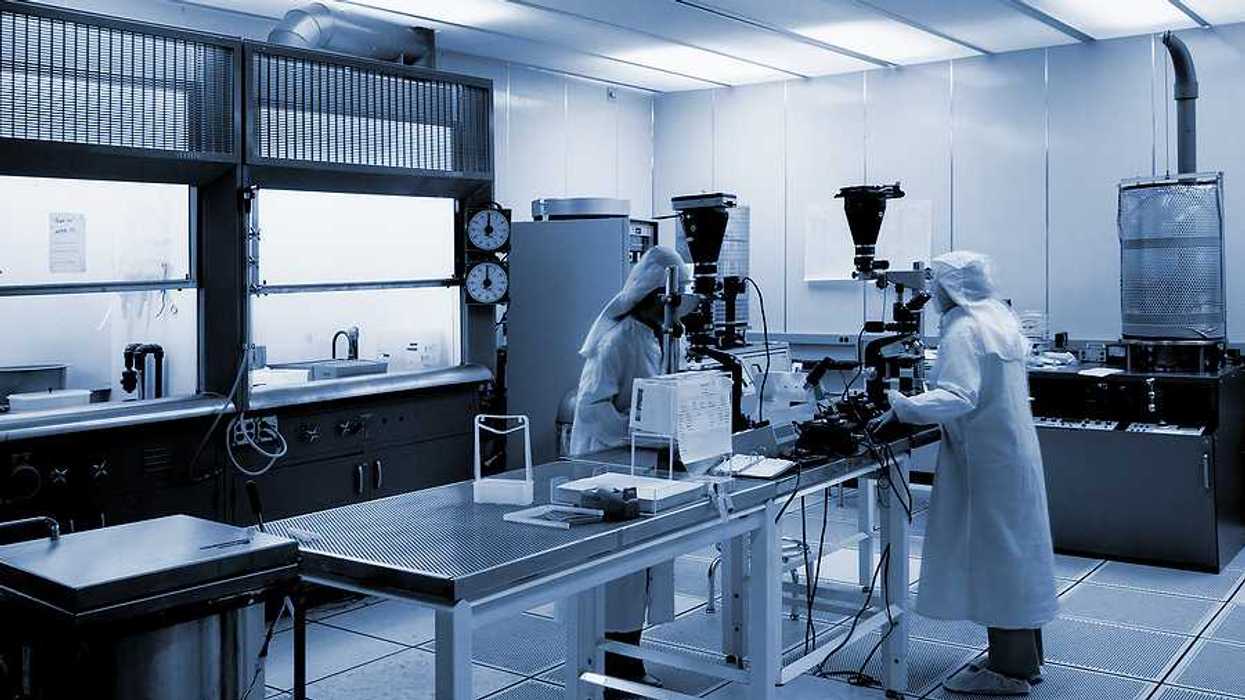 A black and white photo of a lab with two lab workers standing at a table