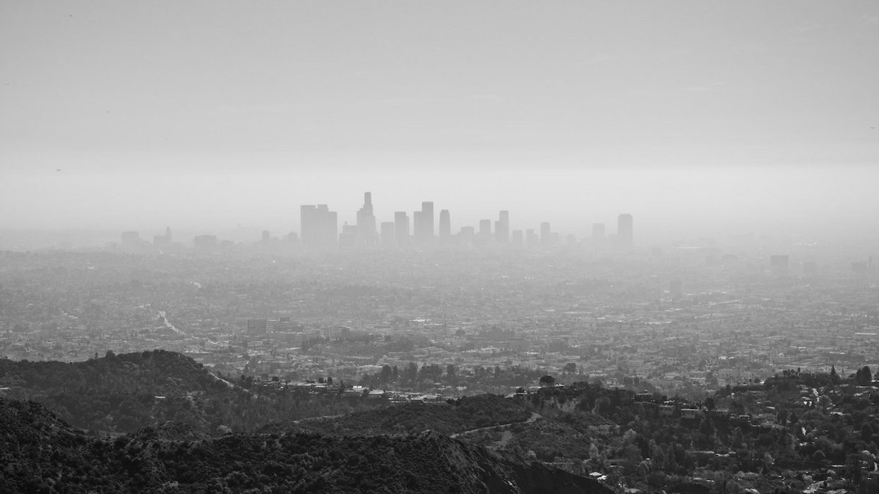 A black-and-white photo of the Los Angeles skyline shrouded in pollution as viewed from nearby mountains.