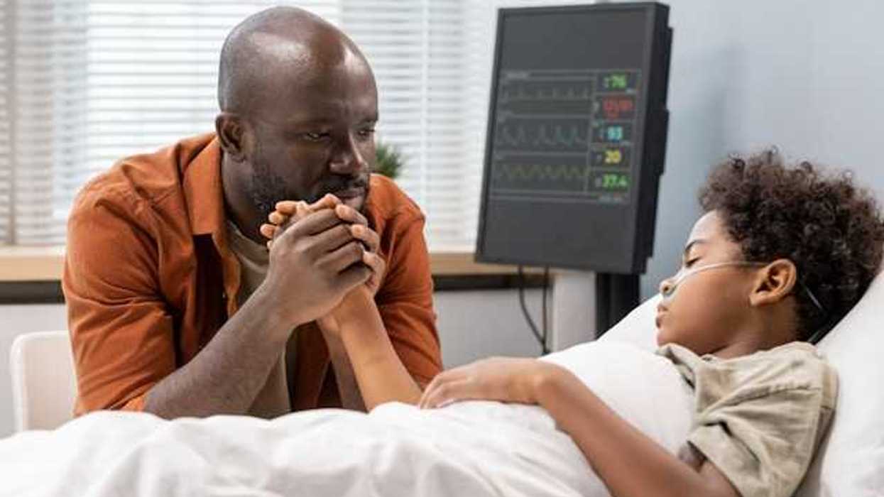 A Black man sitting at the hospital bedside of his son