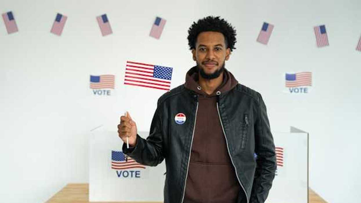 A Black man standing in front of a voting booth