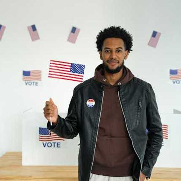 A Black man standing in front of a voting booth