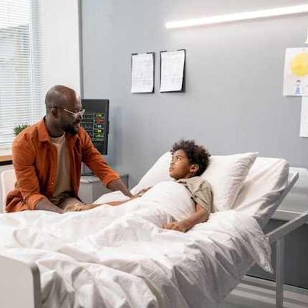 A Black man talking to his child in a hospital bed