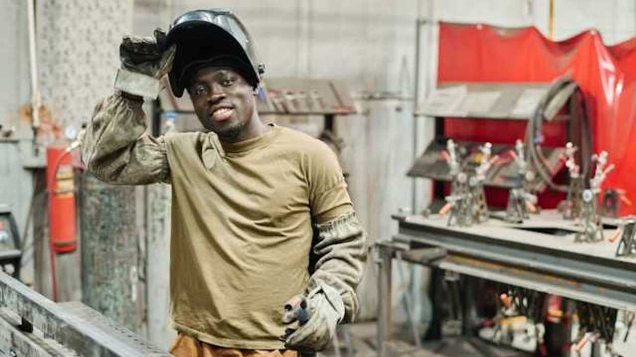 A Black man wearing protective clothing in a manufacturing facility