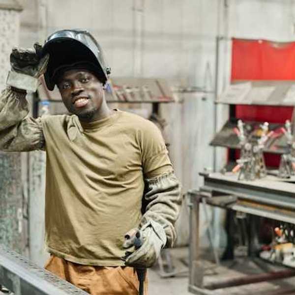 A Black man wearing protective clothing in a manufacturing facility