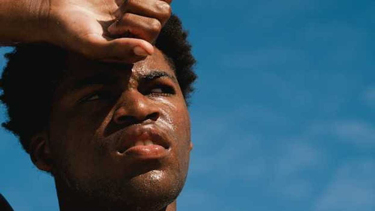 A Black man with perspiration on his face on a sunny day