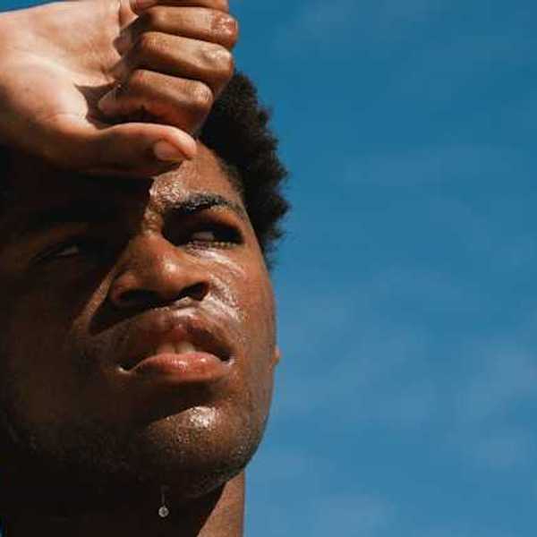 A Black man with perspiration on his face on a sunny day
