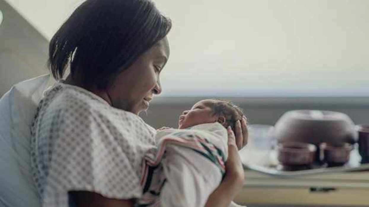 A Black women holding her newborn infant in a hospital room