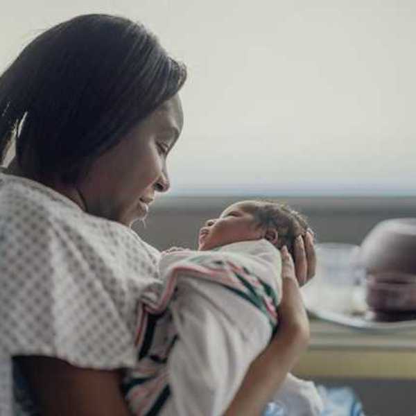 A Black women holding her newborn infant in a hospital room