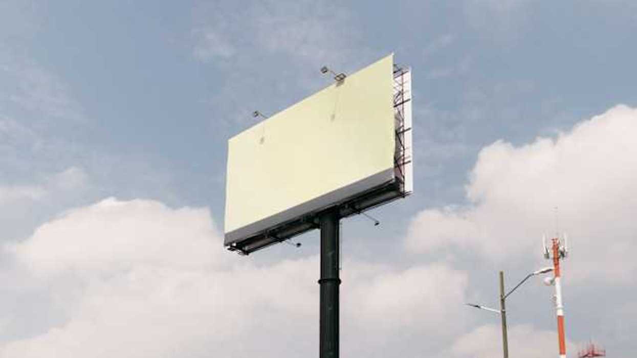 A blank billboard against a blue sky with clouds