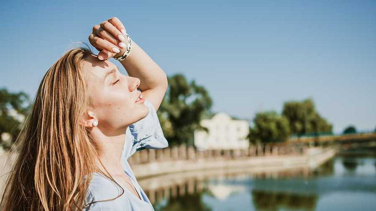 A blonde woman shading her face from the sun