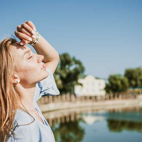 A blonde woman shading her face from the sun