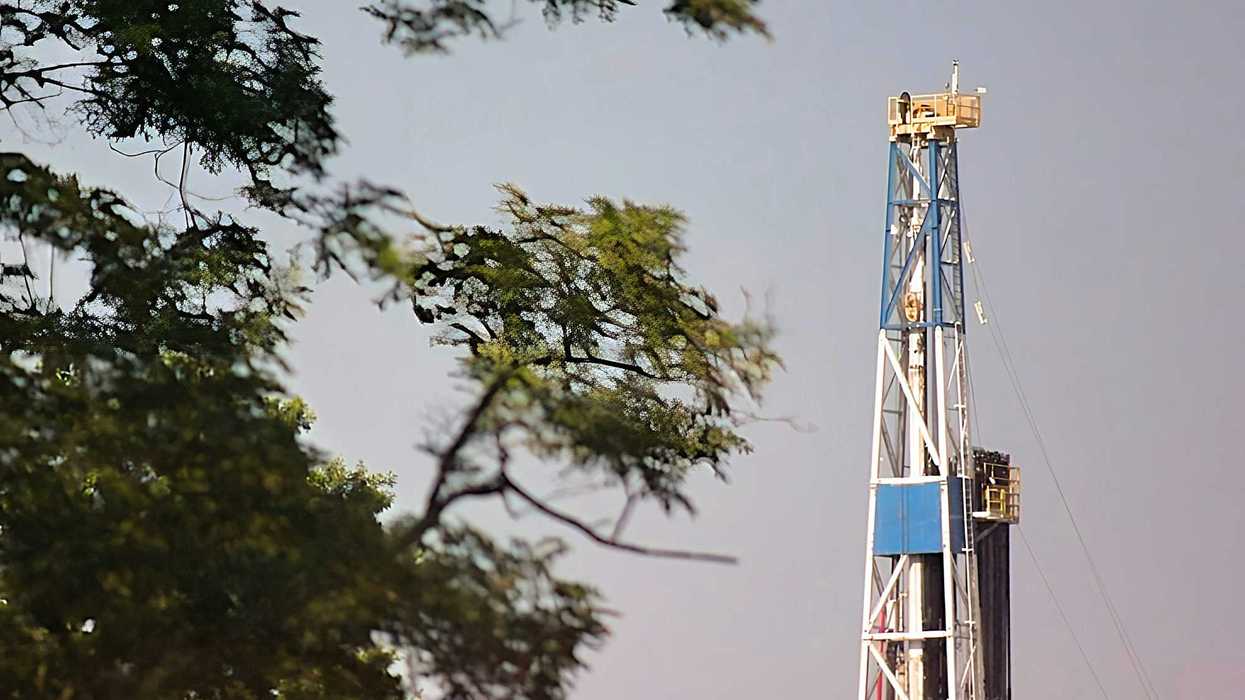 a blue and white drilling rig next to a tree.