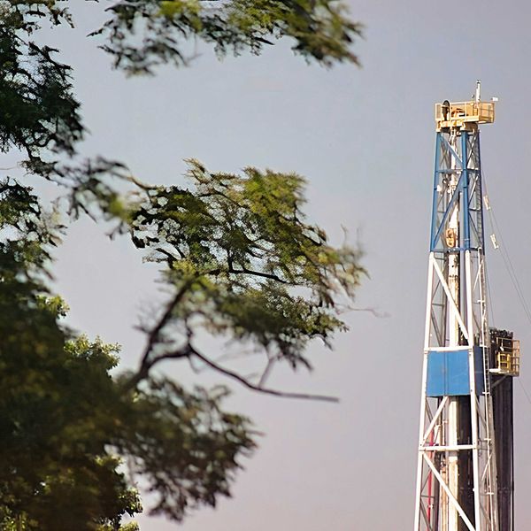 a blue and white fracking drilling rig next to a tree.