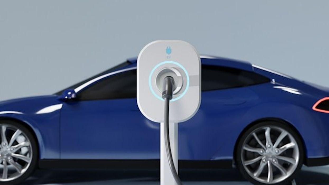 A blue electric vehicle being charged at an EV charging station.