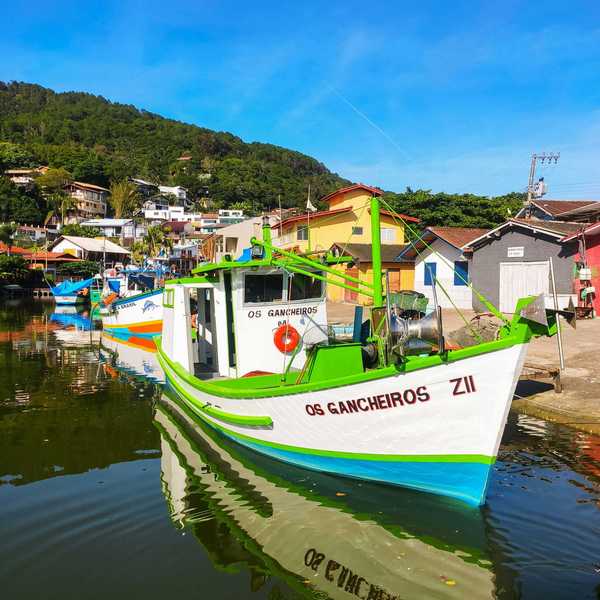 a boat is parked on the water with a village and green hillside in background.