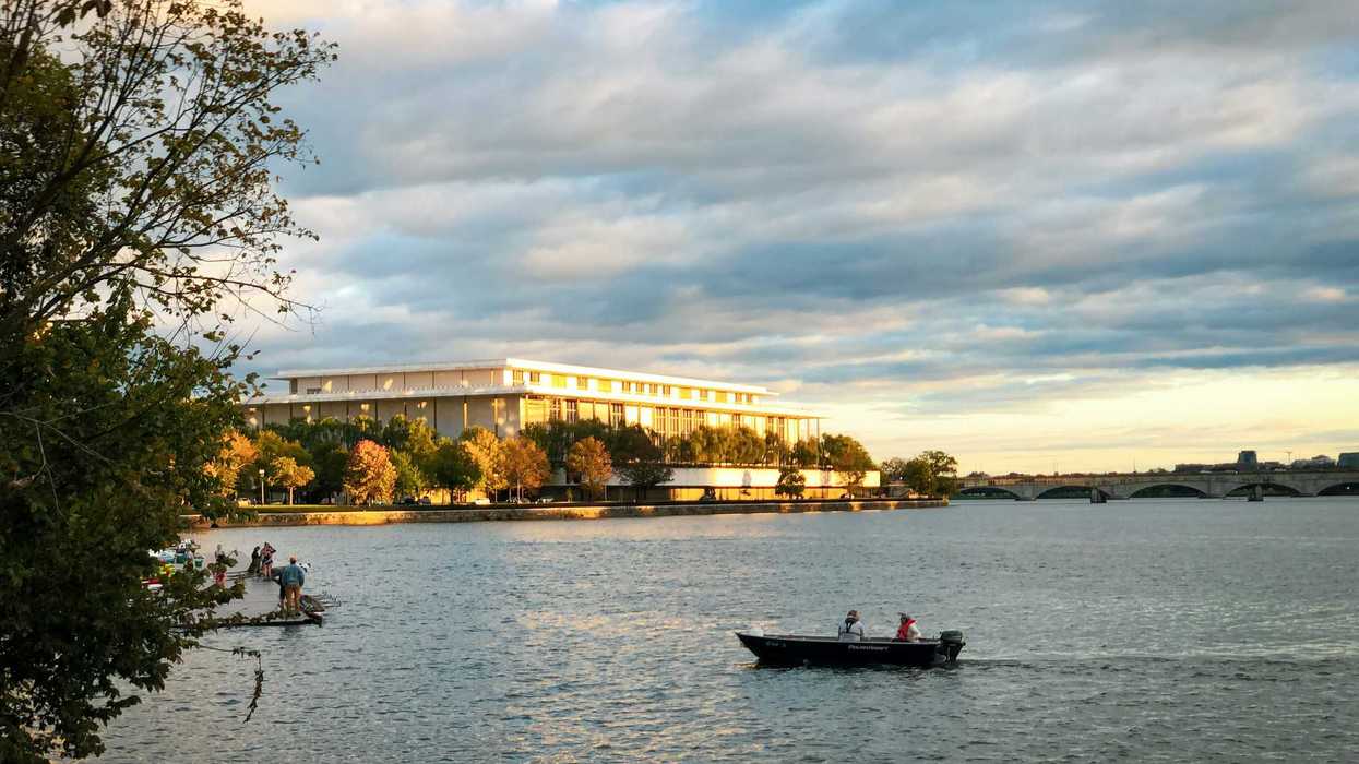 a boat on a body of water with a building in the background.