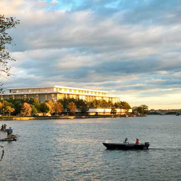 a boat on a body of water with a building in the background.