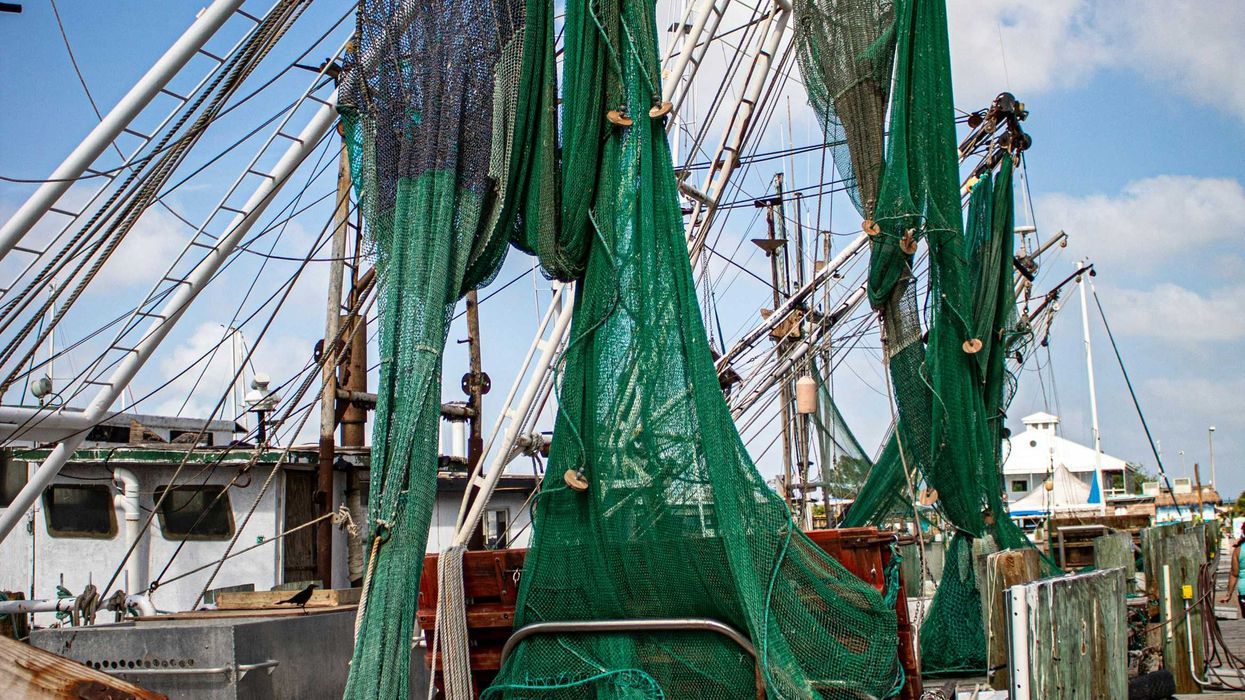 A boat with green fishing nets alongside a dock.