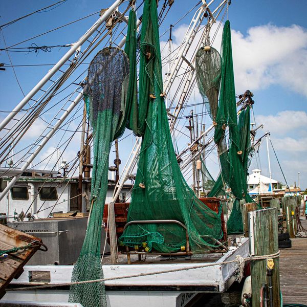 A boat with green fishing nets alongside a dock.