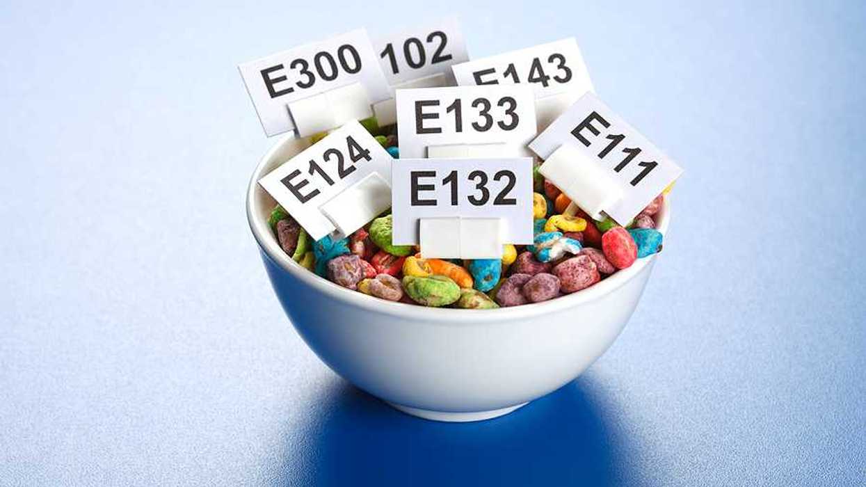 A bowl of multicolored children's cereal with tags showing chemical numbers