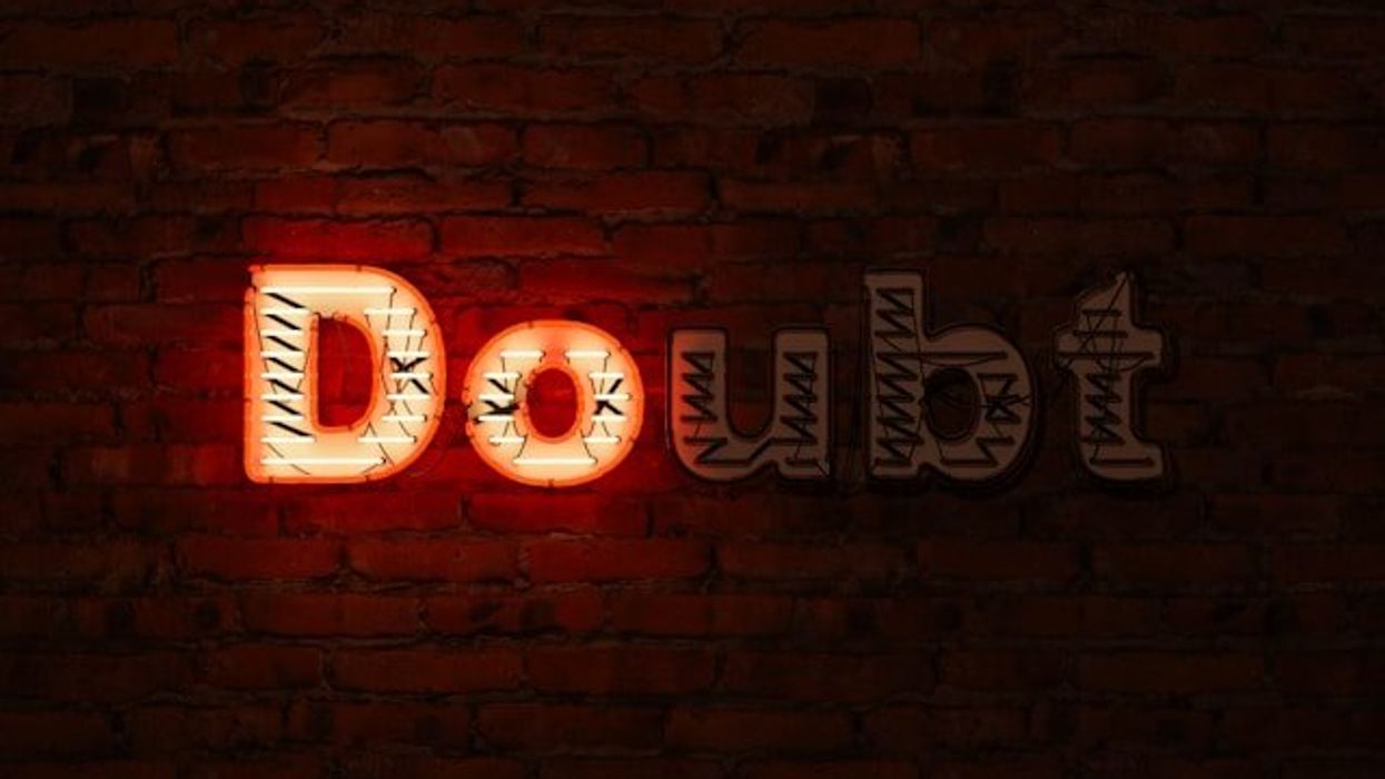 A brick wall with the word Doubt on it, with the D and the O illuminated in red.