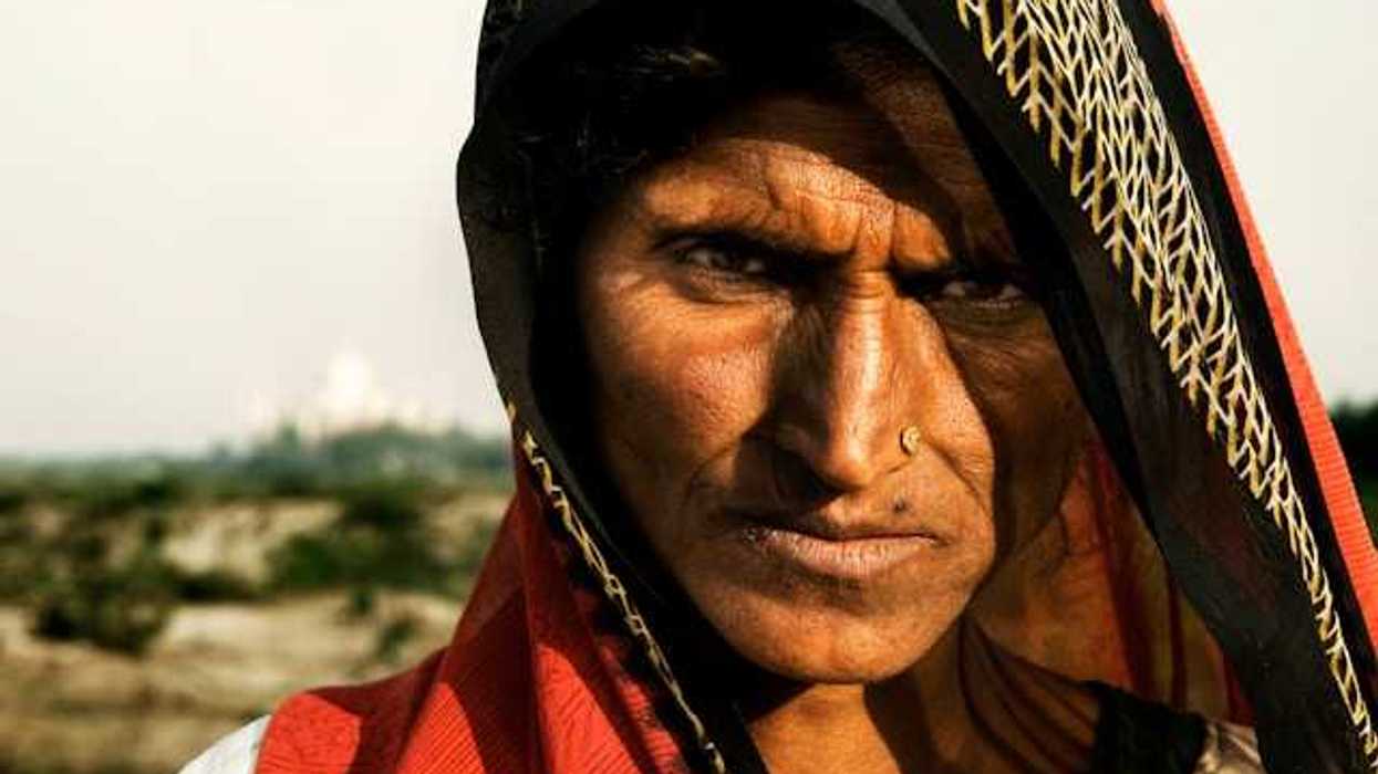 A brown-skinned woman in a colorful veil on a sunny day looking at the camera