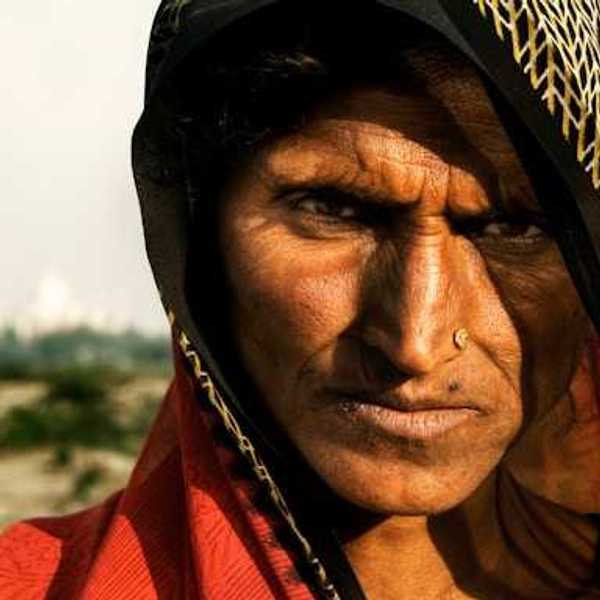 A brown-skinned woman in a colorful veil on a sunny day looking at the camera