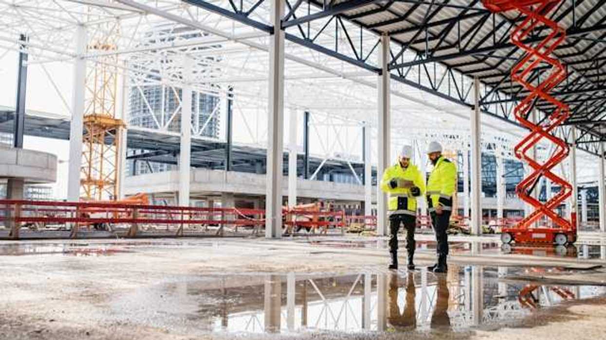A building site with two men in yellow jackets looking at a tablet